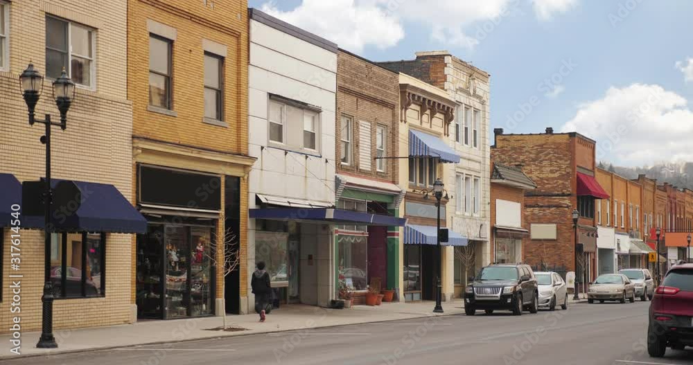 A daytime long shot establishing shot view of middle class businesses on the main street of a small town.  	