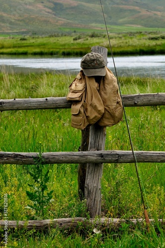 A fly fisherman's geart rests against a rustic wood fence at Silver Creek, Idaho, USA
