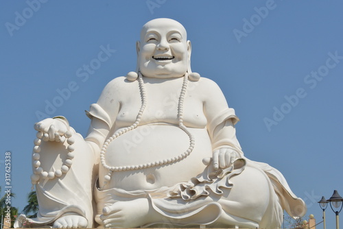 Happy Seated Buddha in Sunshine and Blue Sky in Vietnam