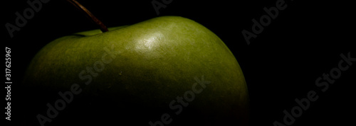 Long background with green apple in contrast light