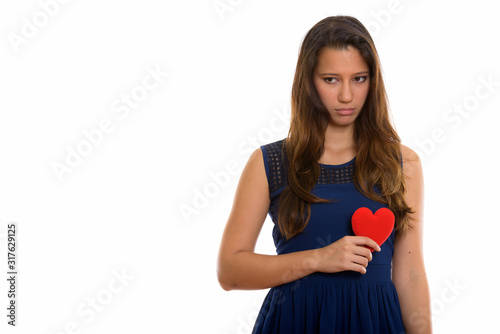 Portrait of sad young woman holding heart while looking down