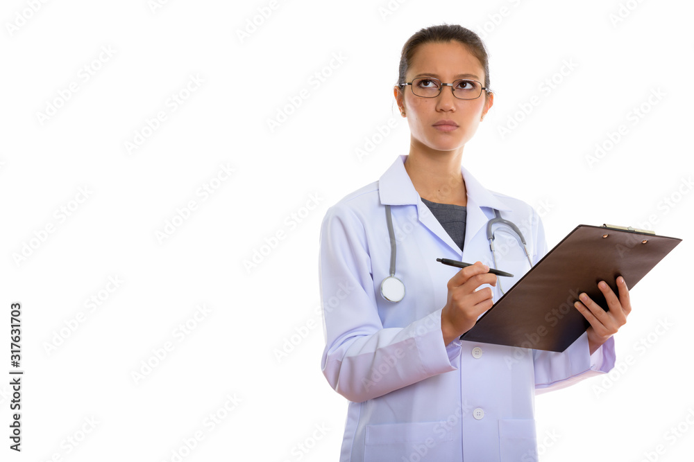Young beautiful woman doctor thinking while writing on clipboard Young beautiful woman doctor thinking while writing on clipboard