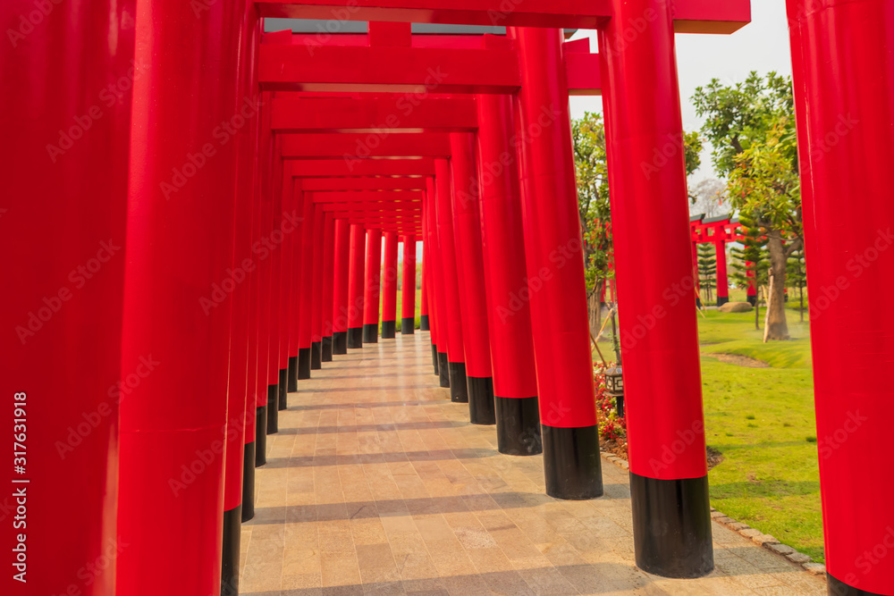 Walkway with red pillars to go green grass field and flower garden , Landscaping in the garden , Shaded walkway in the morning . Walkway with red pillars to go green grass field and flower garden , Landscaping in the garden , Shaded walkway in the morning .