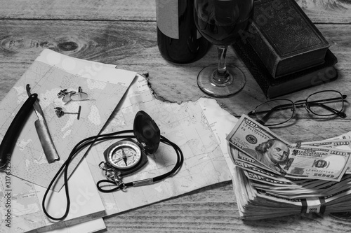 Map, compass, wine, money, books, razor, cuff links, tie tack and glasses, blcack and white, horizontal photo