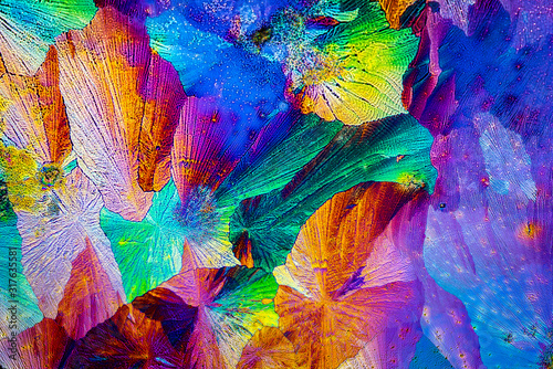 Extreme macro photograph of Paracetamol crystals forming abstract modern art patterns, when illuminated with polarized light, under a microscope objective with 50x magnification