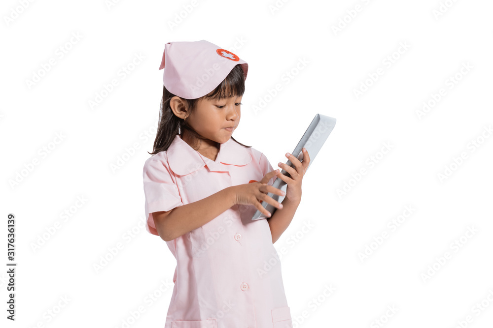 Asian little girl wearing a nurse uniform with hand holding a pad on white background Asian little girl wearing a nurse uniform with hand holding a pad on white background