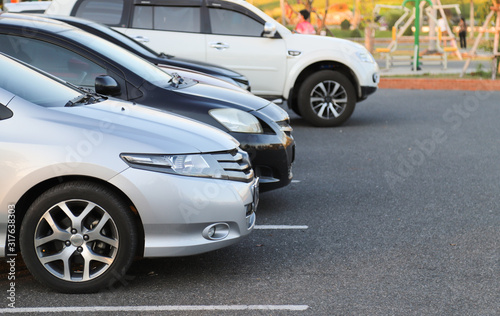 Closeup of front side of bronze, silver car and other cars parking in outdoor parking lot in the evening. © Amphon