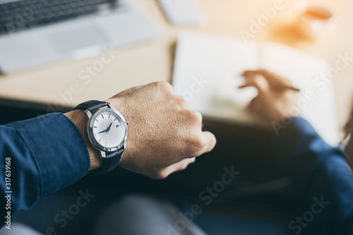 looking at luxury watch on hand check the time at workplace.concept for managing time organization working,punctuality,appointment.fashionable wearing stylish photo