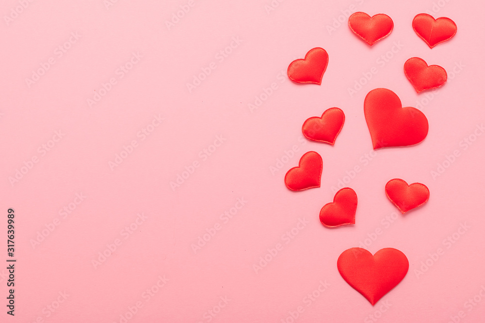 Red hearts symbol of love scattered on pink background. Valentine's day concept. Horizontal frame copy space.