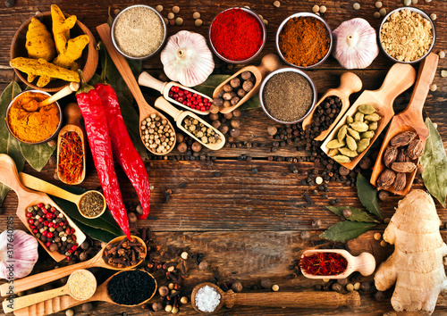 Spices on wooden background. Different pepper powder, peppercorns, ginger, red hot chili pepper, turmeric, saffron, cardamon, sea salt, coriander, bay leaf, cloves. 