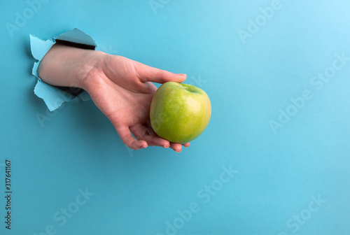The green apple in the woman's hand is made of a hole on a turquoise background