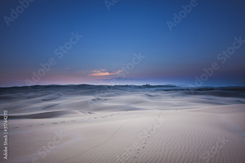Bright unreal contrast desert landscape. Night time mood. A chain of traces stretches to the horizon. Stockton Sand Dunes near the coast, Worimi Regional Park, Anna Bay, Australia