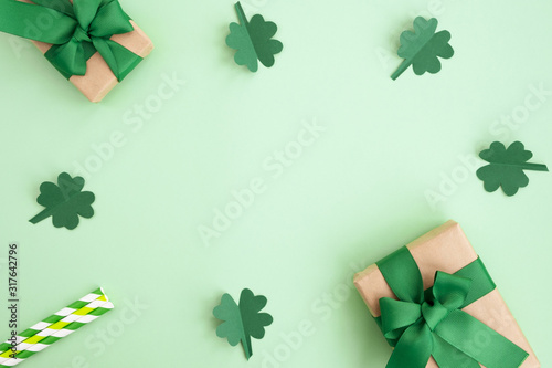 St Patrick's Day composition. Gift boxes, clover and festive decor on a light green background. Top view, flat lay, copy space