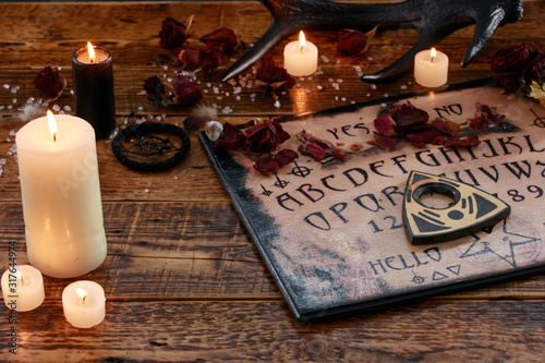 Mystic ritual with Ouija and candles. Devil's board concept, black magic or fortune telling rite with occult and esoteric symbols.