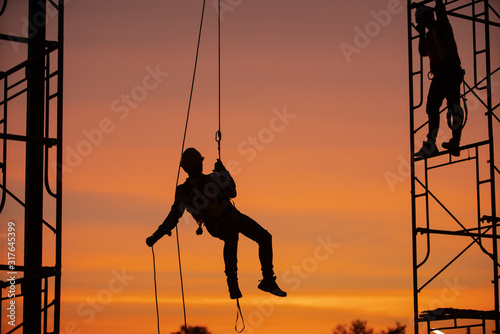 Fényképezés Silhouette Construction site Engineers are abseiling with a zip line