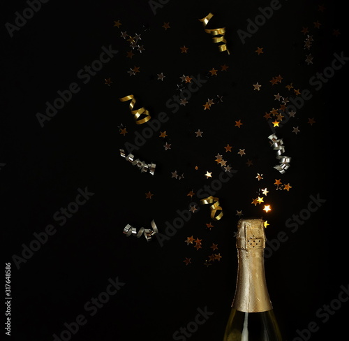 Champagne bottle, gold confetti stars, holiday and party decoration on black ...