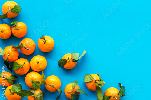 Tangerines with leaves frame on blue background top-down copy space