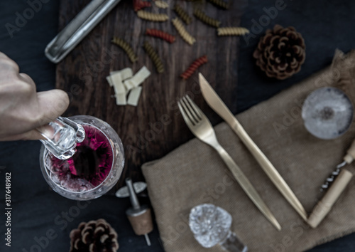 Flat lay composition with pitcher and glasses of red wine and corkscrew on wooden background : traditional winemaking and wine tasting concept.