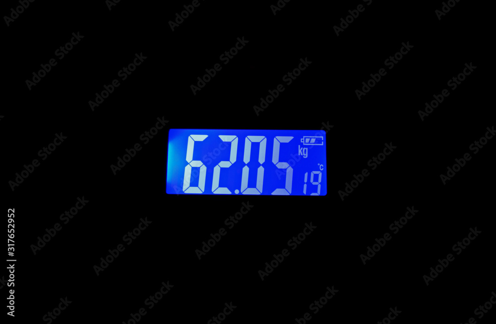 blue display of a digital weight machine displaying weight in kilograms,temperature in degree celcius and battery level. blue display of a digital weight machine displaying weight in kilograms,temperature in degree celcius and battery level.