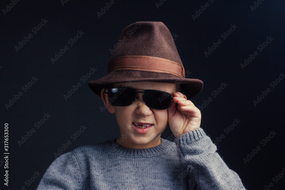 Studio portrait of a boy in a grey sweater, brown hat and sunglasses Studio portrait of a boy in a grey sweater, brown hat and sunglasses