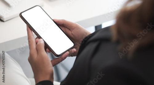 Cropped shot view of woman hands holding smart phone with blank copy space screen for your text message or information content, female reading text message on cell telephone during in urban setting. 