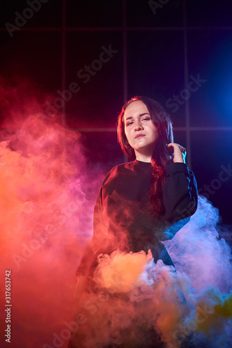 Fototapeta Naklejka Na Ścianę i Meble -  Portrait of chubby teen girl during photoshoot with colored smoke at night and black background