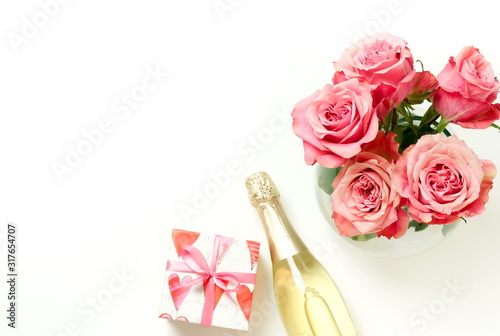 Valentine's day, birthday, romantic background. Bouquet of pink roses flowers, gift box ,champagne bottle and red hearts confetti isolated on white background with copy space. Top view flat lay