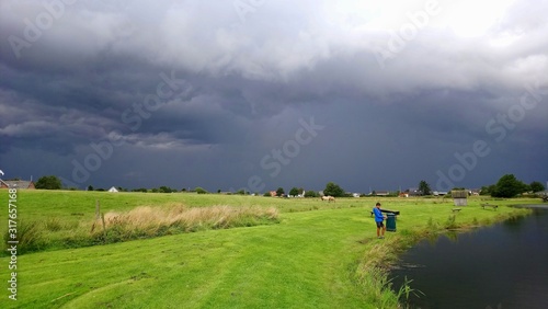 dramatic storm forming over a lush green meadow