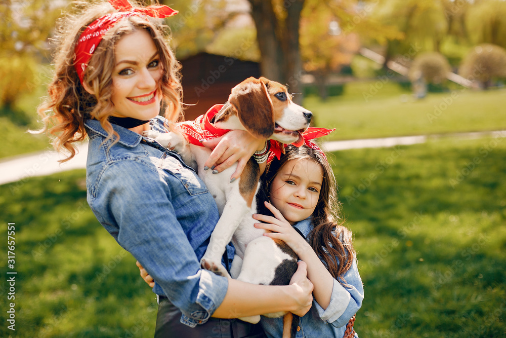 Beautiful mother with daughter. Family in a spring park. Woman in a blue shirt. Family with a cute dog