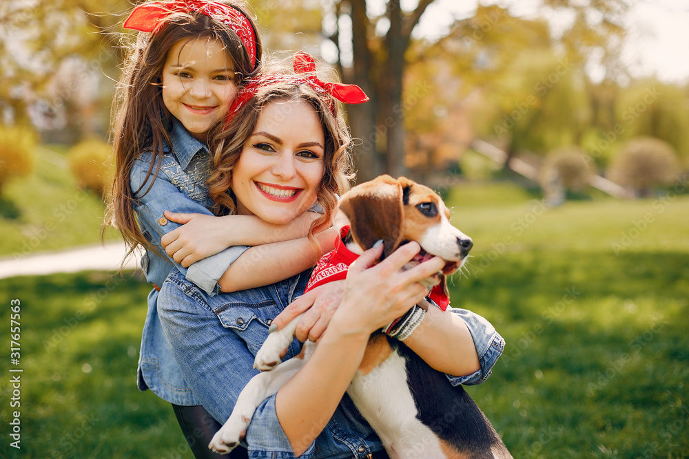 Beautiful mother with daughter. Family in a spring park. Woman in a blue shirt. Family with a cute dog Beautiful mother with daughter. Family in a spring park. Woman in a blue shirt. Family with a cute dog