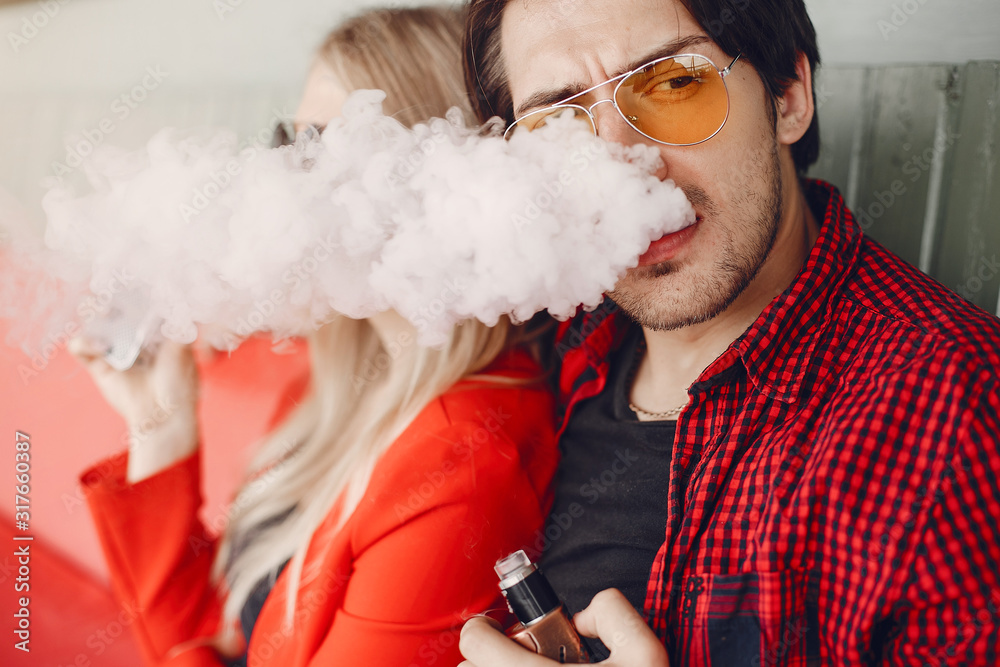 Stylish couple in a city. Two people use the electronic cigarette Stylish couple in a city. Two people use the electronic cigarette