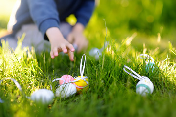 Little boy hunting for easter egg in spring garden on Easter day. Focus on multicolor eggs.