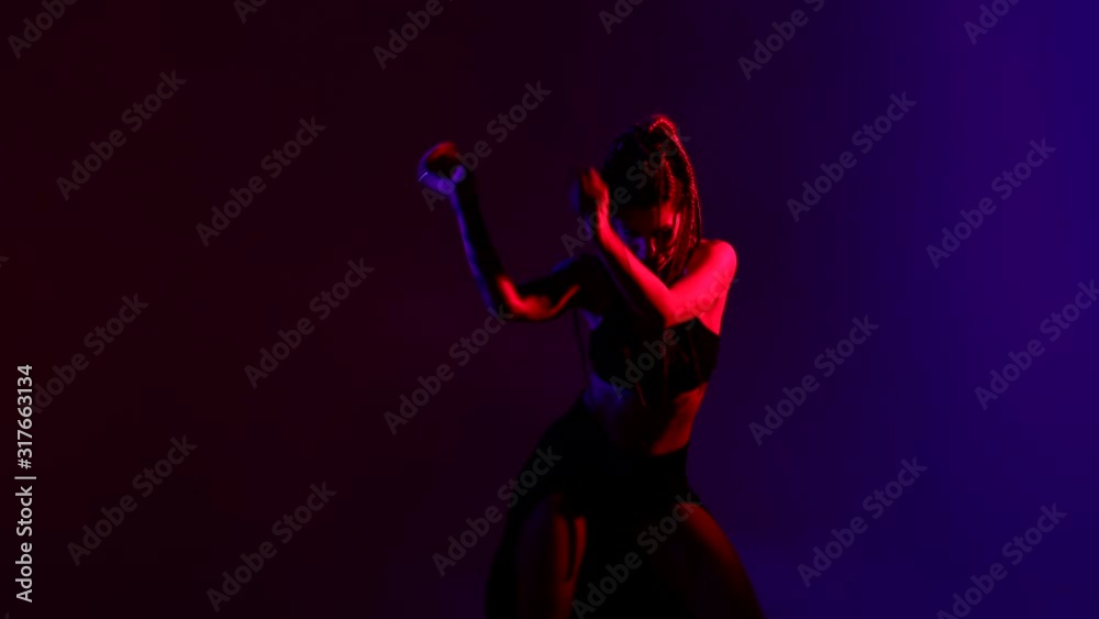 Black dressed and braided hair woman dancing on a blue and red background. Black dressed and braided hair woman dancing on a blue and red background.