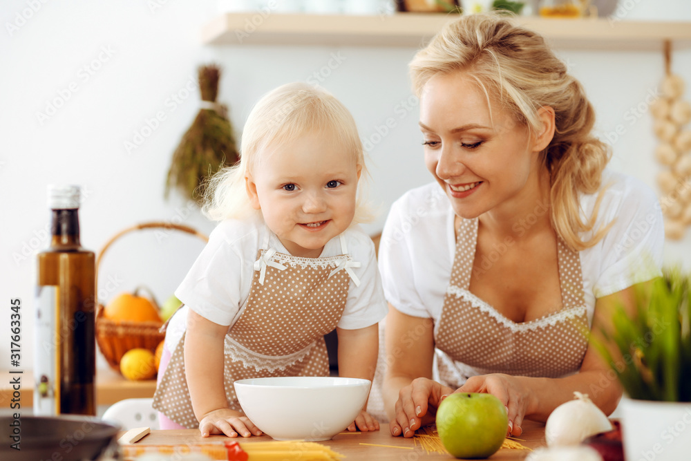 Happy mother and little daughter cooking in kitchen. Spending time all together, family fun concept Happy mother and little daughter cooking in kitchen. Spending time all together, family fun concept