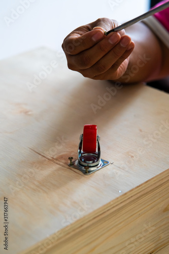 Fixing castor wheel to the wooden plywood, furniture making. photo