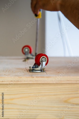 Fixing castor wheel to the wooden plywood, furniture making. photo