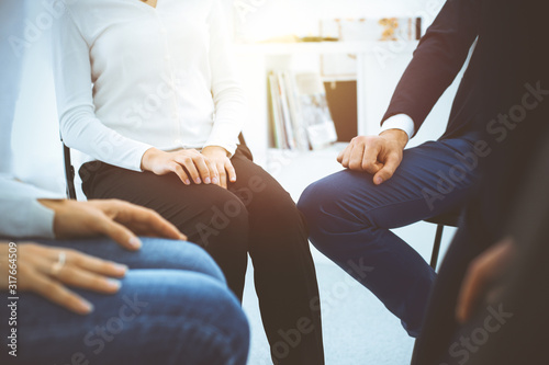 Group of people sitting in a circle during therapy in sunny office. Meeting of business team participating in training