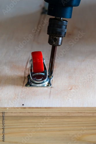 Fixing castor wheel to the wooden plywood, furniture making. photo