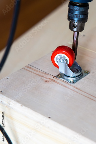 Fixing castor wheel to the wooden plywood, furniture making. photo