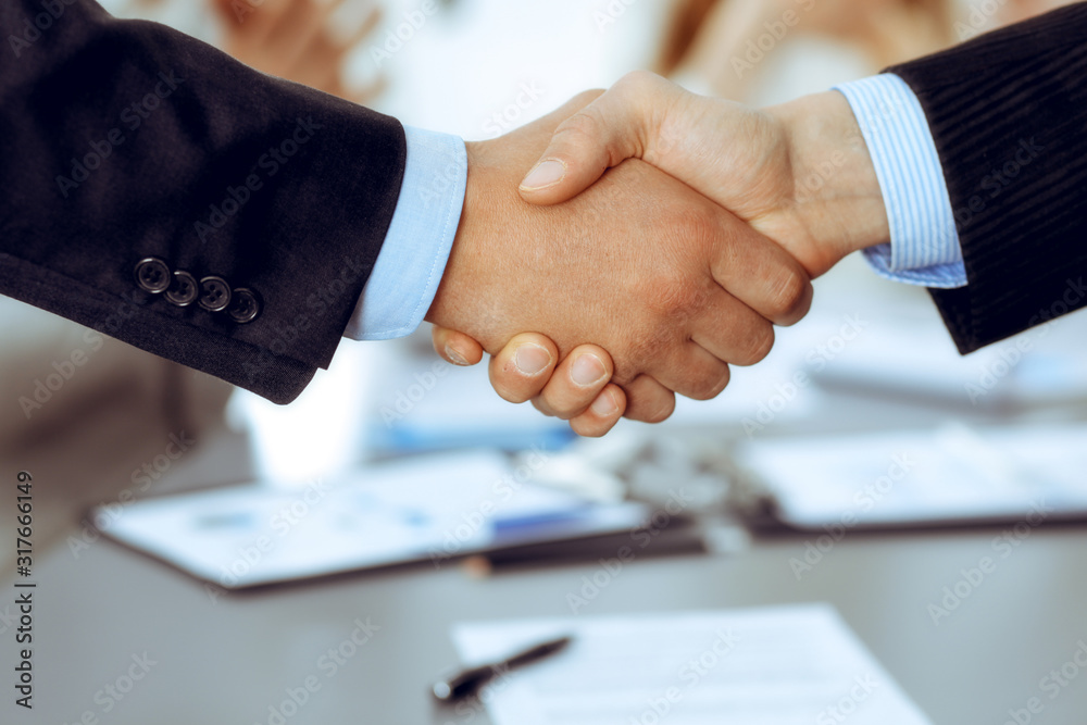 Business people shaking hands at meeting while theirs colleagues clapping and applauding. Group of unknown businessmen and women in modern white office. Success teamwork, partnership and handshake Business people shaking hands at meeting while theirs colleagues clapping and applauding. Group of unknown businessmen and women in modern white office. Success teamwork, partnership and handshake