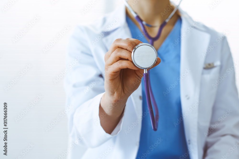 Unknown doctor woman holds stethoscope head, close-up. Physician ready to examine and help patient. Helping and insurance in health care, best treatment and medicine concept Unknown doctor woman holds stethoscope head, close-up. Physician ready to examine and help patient. Helping and insurance in health care, best treatment and medicine concept