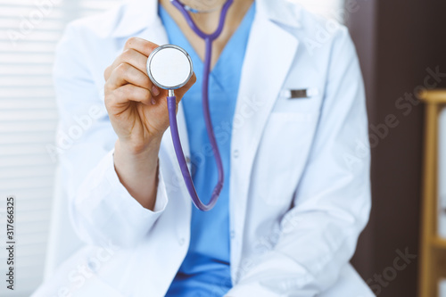 Unknown doctor woman holds stethoscope head, close-up. Physician ready to examine and help patient. Helping and insurance in health care, best treatment and medicine concept