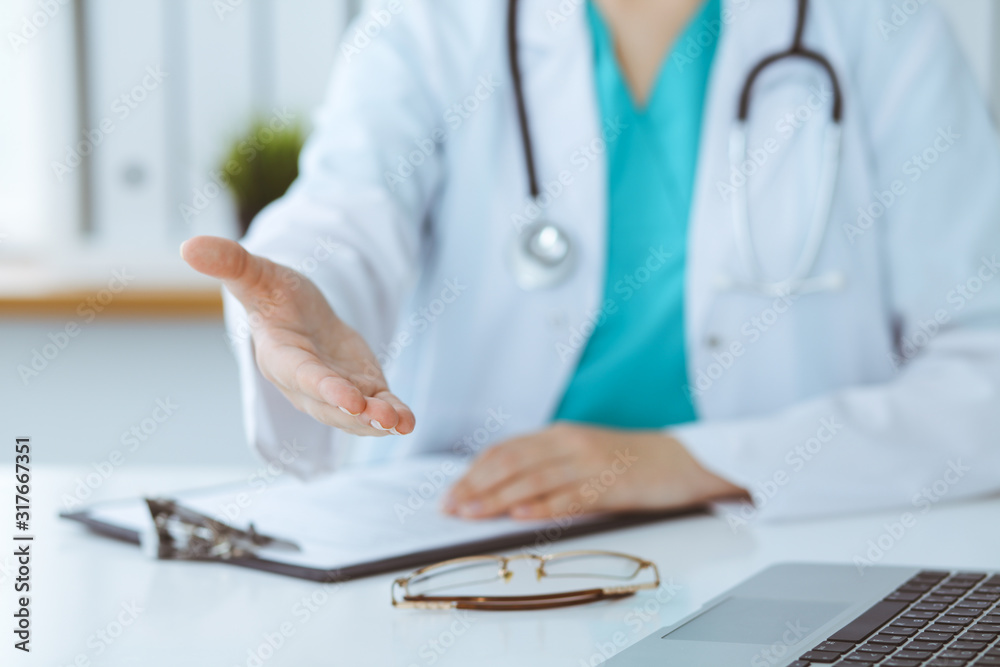 Female medicine doctor offering helping hand in office closeup. Physician ready to examine and save patient. Friendly and cheerful gesture