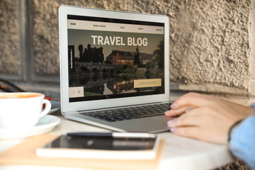 Female travel blogger with laptop in cafe, closeup