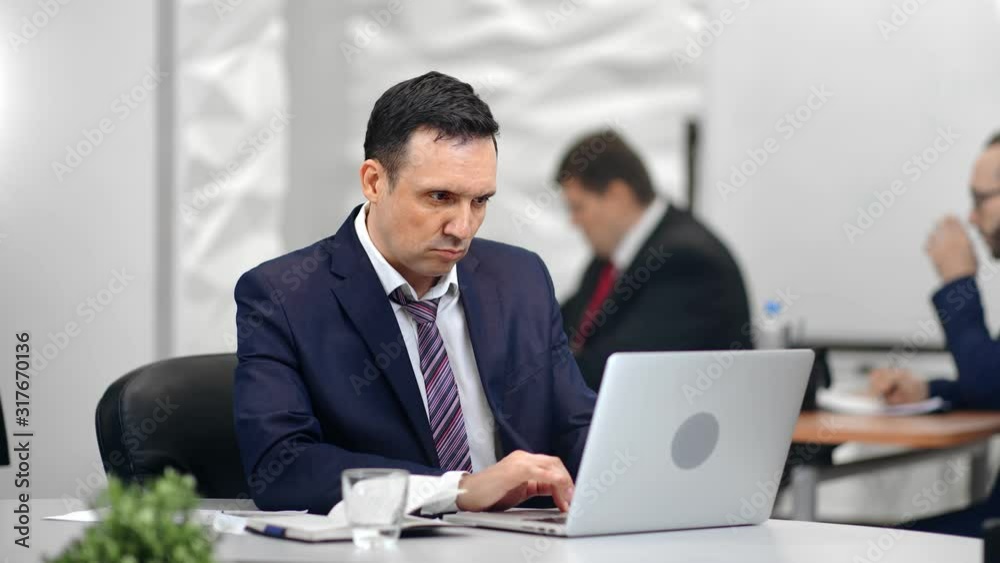 Stylish busy man boss typing using computer pc at workplace coworkers people background Stylish busy man boss typing using computer pc at workplace coworkers people background