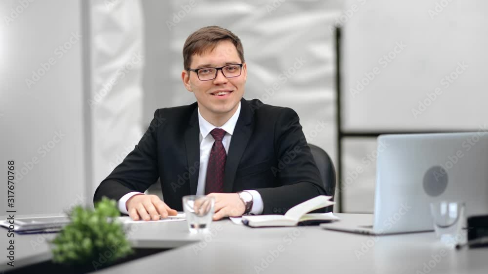 Stylish young office worker in glasses posing at workplace medium shot on red camera Stylish young office worker in glasses posing at workplace medium shot on red camera