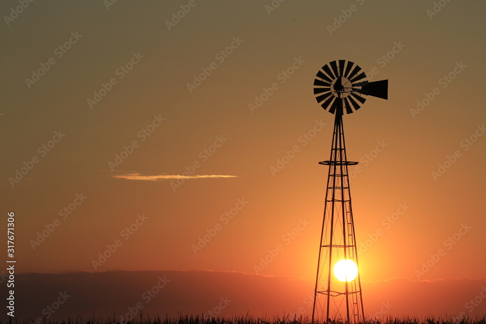 windmill at sunset in Kansas with a colorful sky.