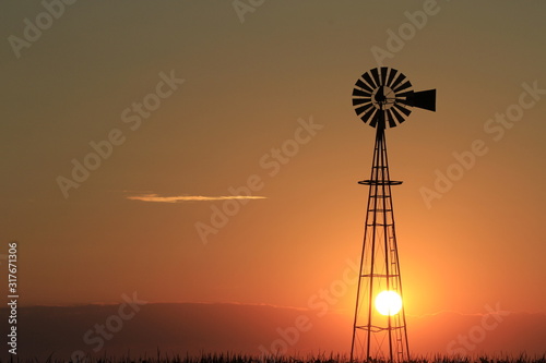windmill at sunset in Kansas with a colorful sky. © Stockphotoman