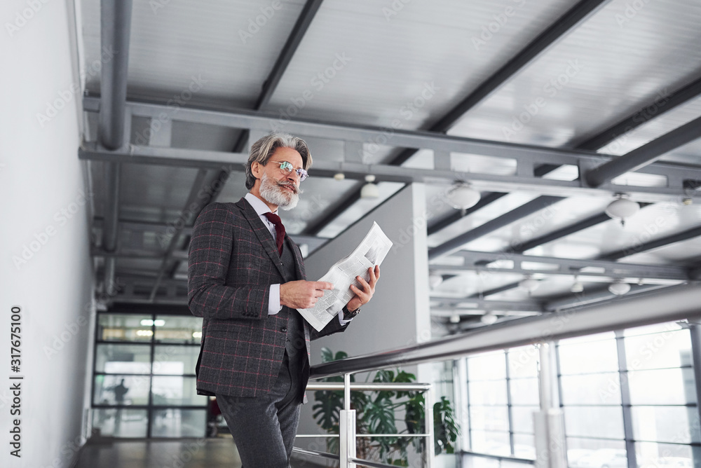 Senior businessman in suit and tie with gray hair and beard holds documents in hands Senior businessman in suit and tie with gray hair and beard holds documents in hands