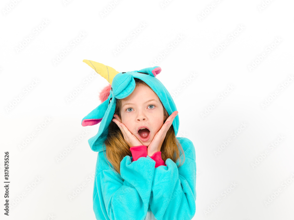 pretty blonde girl with cozy blue unicorn costume is posing in the studio in front of white wall and is happy pretty blonde girl with cozy blue unicorn costume is posing in the studio in front of white wall and is happy